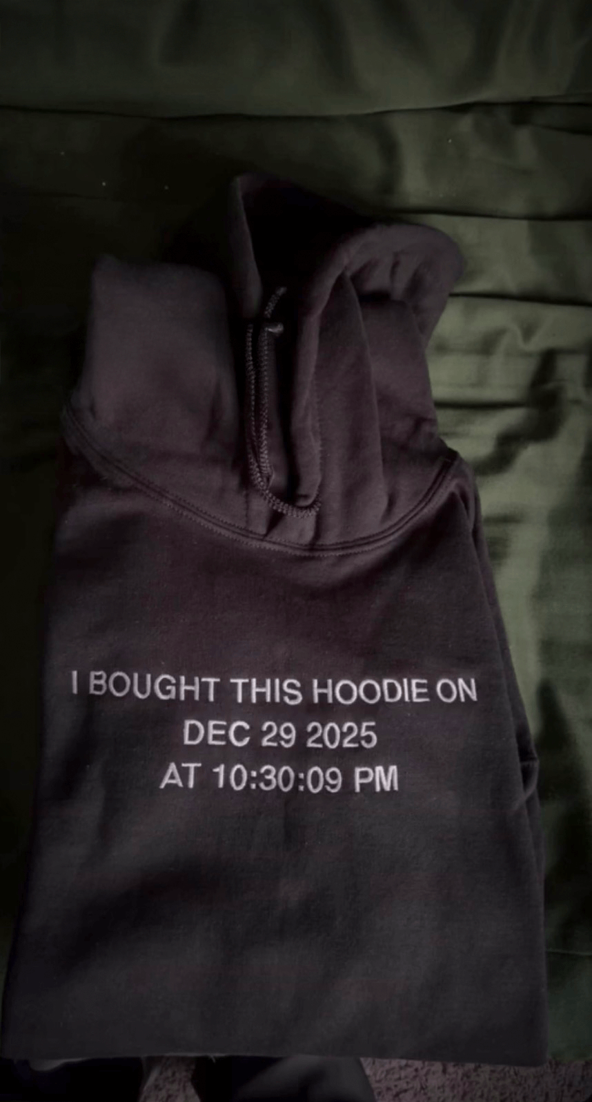Dark hoodie embroidered with timestamp on a green background